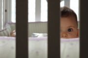 baby peering through crib slats